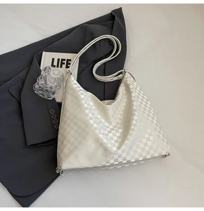 Detail of checkered tote bag with silver metal hooks on a grey blazer backdrop