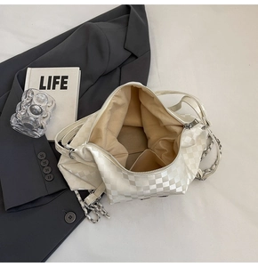 Detail of checkered tote bag interior with inner pocket and woven metal chain strap