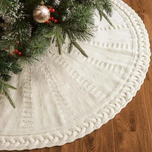 Detailed knit texture of ivory Christmas tree skirt with thick cable pattern on wood floor