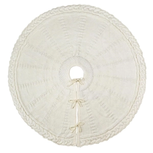 Close-up of cream knitted Christmas tree skirt with cable knit patterns and ribbon bows
