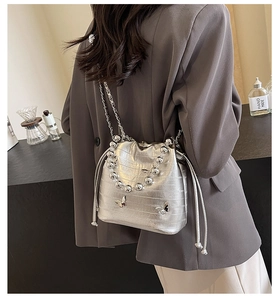 Silver bucket bag with crocodile texture and 3D metal butterfly detail on chain strap