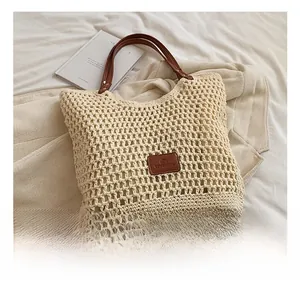 Detail of hand-woven crochet beach tote bag with brown leather handles and logo
