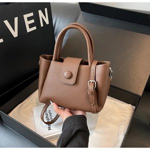 Close-up of brown lychee grain leather bucket bag with round buckle and top handles
