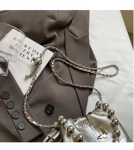 Detailed macro view of silver bucket bag with crocodile texture and butterfly buckle