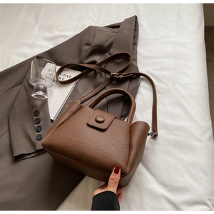 Close-up of retro dark brown lychee leather bucket bag with a round buckle detail
