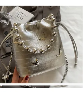 Detail of silver bucket bag featuring crocodile pattern, butterfly motifs, and beaded handle