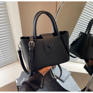 Detail of black lychee grain leather tote bag with round handle and adjustable strap