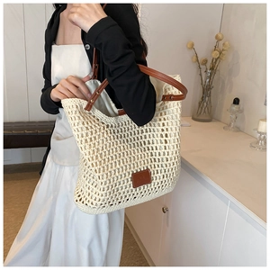 Detail of hollow woven tote bag with brown leather straps and rivet reinforcements