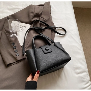 Close-up of black lychee grain leather bucket bag with top handles and adjustable strap