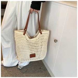 Detail view of hollow crochet tote bag with leather straps and logo patch