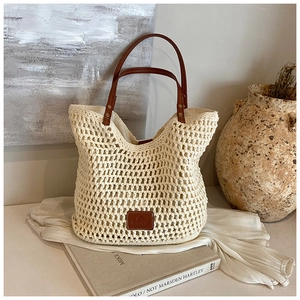 Detail of beige woven tote bag with brown leather handles and a textured crochet finish