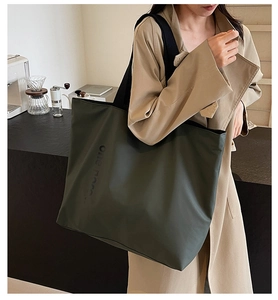 Detail of dark olive green tote bag featuring 3D embossed text and matte texture