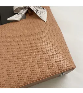 Détail de la texture en cuir tressé marron avec foulard en soie et rivets de protection