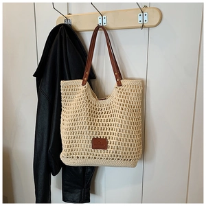 Detail of hollow woven tote bag featuring brown leather straps and rivet accents