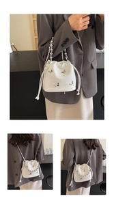 Detail of white crocodile bucket bag featuring silver butterfly accents and beaded handle
