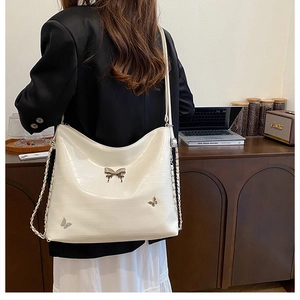Dettaglio della borsa in pelle bianca con farfalle metalliche e tracolla a catena
