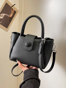 Minimalist black lychee leather bucket bag with top handle and crossbody strap