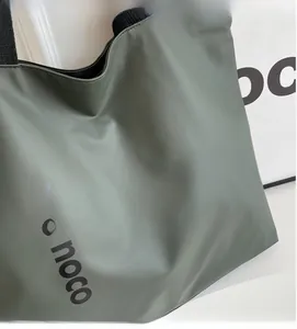 Detail of the morandi green nylon tote bag featuring a black one noco printed logo