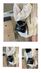 Detail of black crocodile texture bucket bag with silver beads and butterfly accents