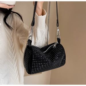 Detail of black rhinestone cylinder bag with silver chain worn on white knit sweater