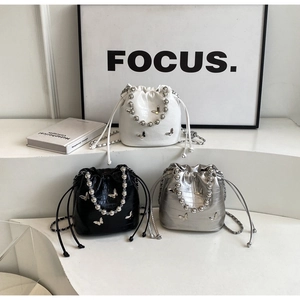 Detailed close-up of stylish bucket bags with silver butterfly charms and beaded handles