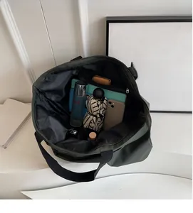 Top view of spacious dark green nylon tote interior with compartments for daily essentials