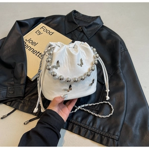 Detail of white crocodile texture bucket bag with silver metal butterfly and bead handle
