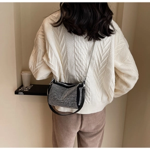 Close-up of black crossbody bag with silver studs and chain strap on model
