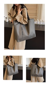 Detail of large grey nylon tote bag showing durable fabric and wide black shoulder straps