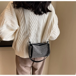 Detail of crossbody bag with silver studs and chain strap on a knit sweater