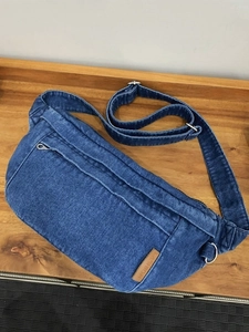 Borsa a tracolla in denim blu con cuciture vintage e logo in pelle su legno