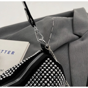 Detailed macro view of the silver zipper and metal chain clasp on a black rhinestone bag