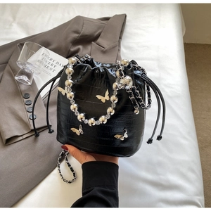 Detail of black crocodile embossed bucket bag with silver bead handle and butterfly charms