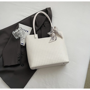 Détail d'un sac cabas tissé blanc avec foulard en soie à motif bambou et pieds en métal