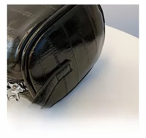 Detailed close-up of premium black glossy leather surface and precision stitching on bag