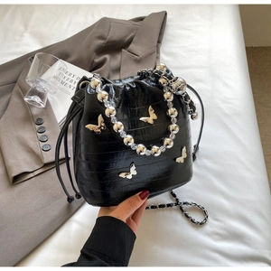 Detail of black crocodile texture bucket bag with metal butterfly and silver bead handle