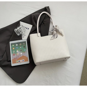 Détail d'un sac cabas tissé blanc avec foulard en soie floral et clous en métal argenté