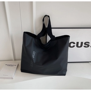 Detail shot of the black nylon tote bag featuring minimalist logo and durable shoulder strap