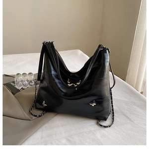 Dettaglio della borsa Hobo in pelle testurizzata nera con ciondoli a farfalla in argento