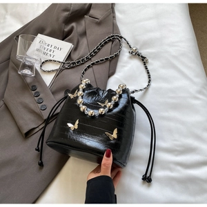 Detail of black bucket bag with silver beads, butterfly charms, and drawstring closure