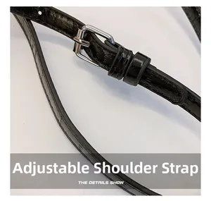 Close-up of adjustable black crocodile embossed leather shoulder strap with silver buckle