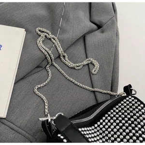 Macro detail of sparkly silver rhinestones and metal chain on black crossbody bag