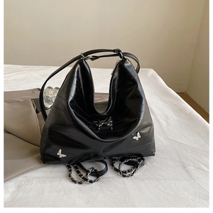 Dettaglio borsa hobo con stampa lucertola, ciondoli a farfalla e catene argento