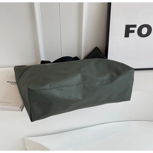 Macro detail of spacious army green nylon tote bag with reinforced stitching and straps