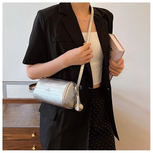 Detail of silver cylindrical crossbody bag with fine texture and metal ball charm decoration