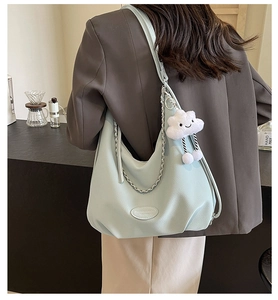 Close-up of light blue pebbled leather hobo bag with silver chain and plush cloud charm