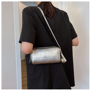 Close-up of metallic silver pillow bag with smooth texture and hanging metal ball charm