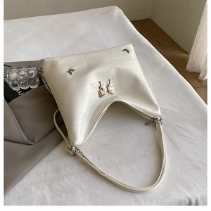 Dettaglio borsa hobo in finta pelle di coccodrillo bianco crema con farfalle argentate