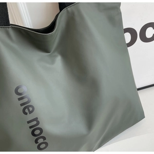 Detail of olive green tote bag showing smooth fabric texture and branded side lettering