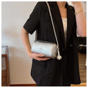 Detail of silver cylindrical crossbody bag featuring embossed texture and logo